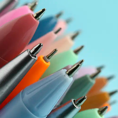 Un primer plano de las puntas y los cuerpos superiores de varias plumas de diferentes colores (rosa, azul claro, naranja, gris) en un fondo azul, con algunas desenfocadas en la distancia.